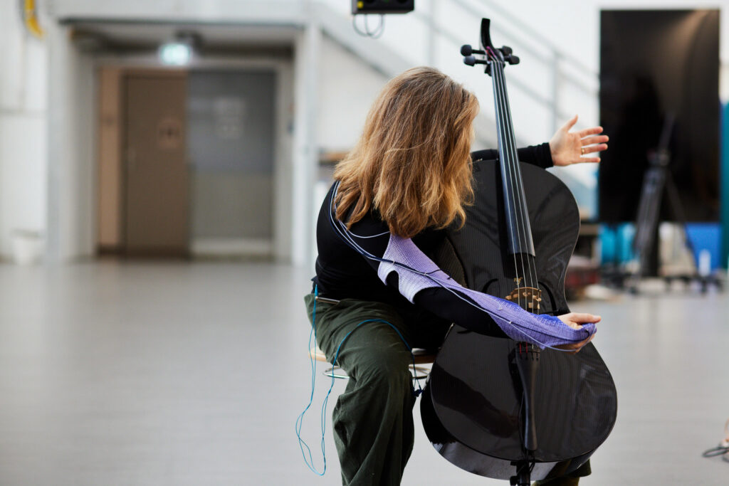 A cello player wearing an interactive textile sleeve making expressive movement of cello playing